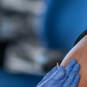 Medical professional places bandage on vaccine spot