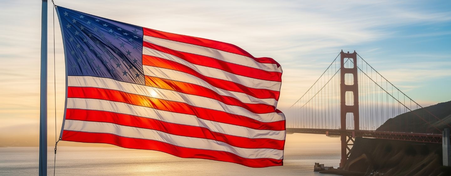 American flag backlit by evening sun and the Golden Gate Bridge in the distance