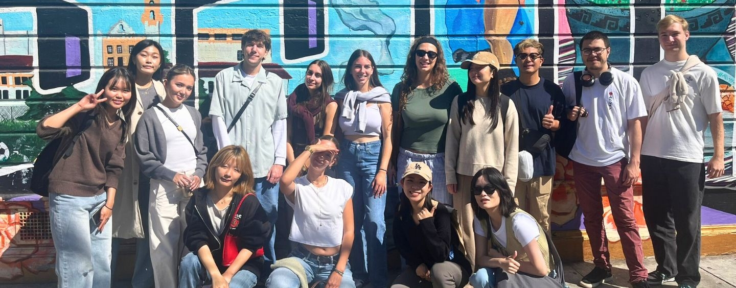 International student group poses in front of a mural